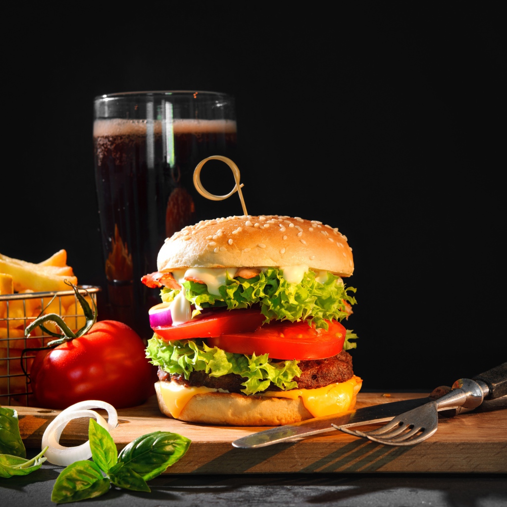 Вкусный аппетитный гамбургер на столе с пивом и картофелем фри