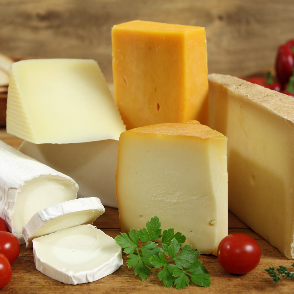 Разные виды твердого сыра на столе с помидорами и петрушкой