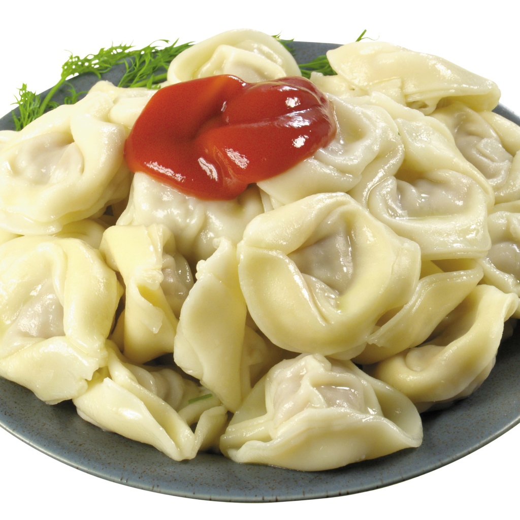 Пельмени в тарелке с кетчупом на белом фоне