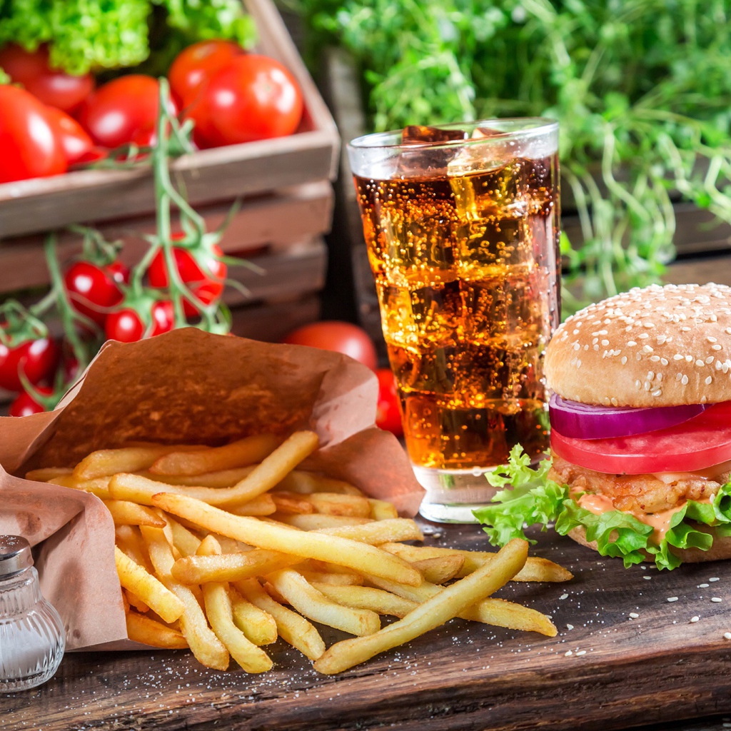 Картофель фри, гамбургер, кола и помидоры на столе