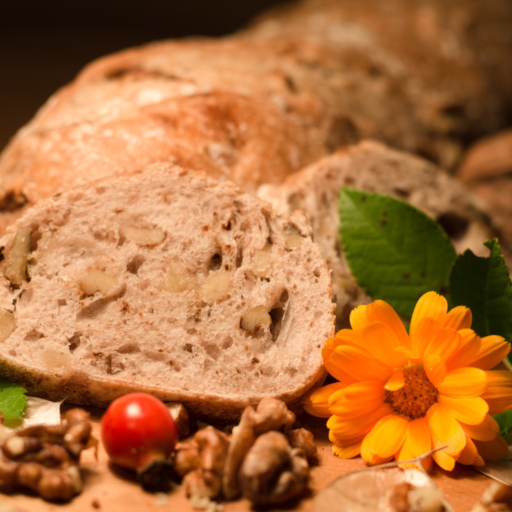 Свежий хлеб с грецкими орехами и цветами календулы на столе