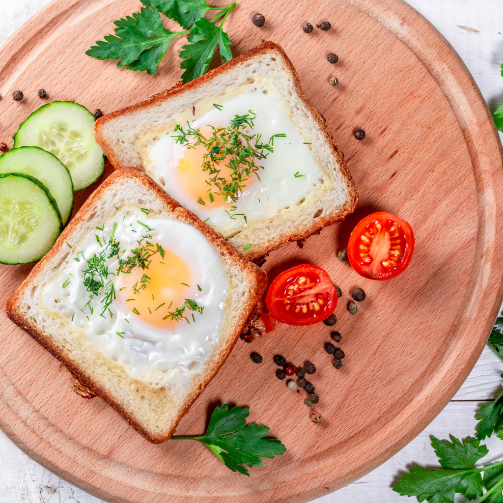 Яичница в хлебе на доске с помидорами, огурцами и петрушкой