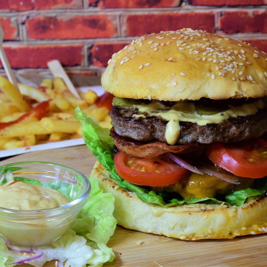 Гамбургер с беконом на столе с соусом и картофелем фри