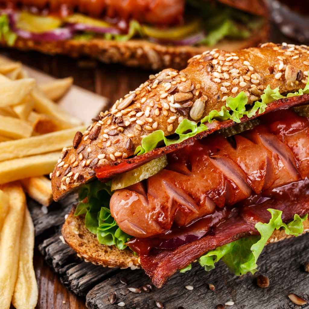 Хотдог с сосиской и беконом на столе с картофелем фри 