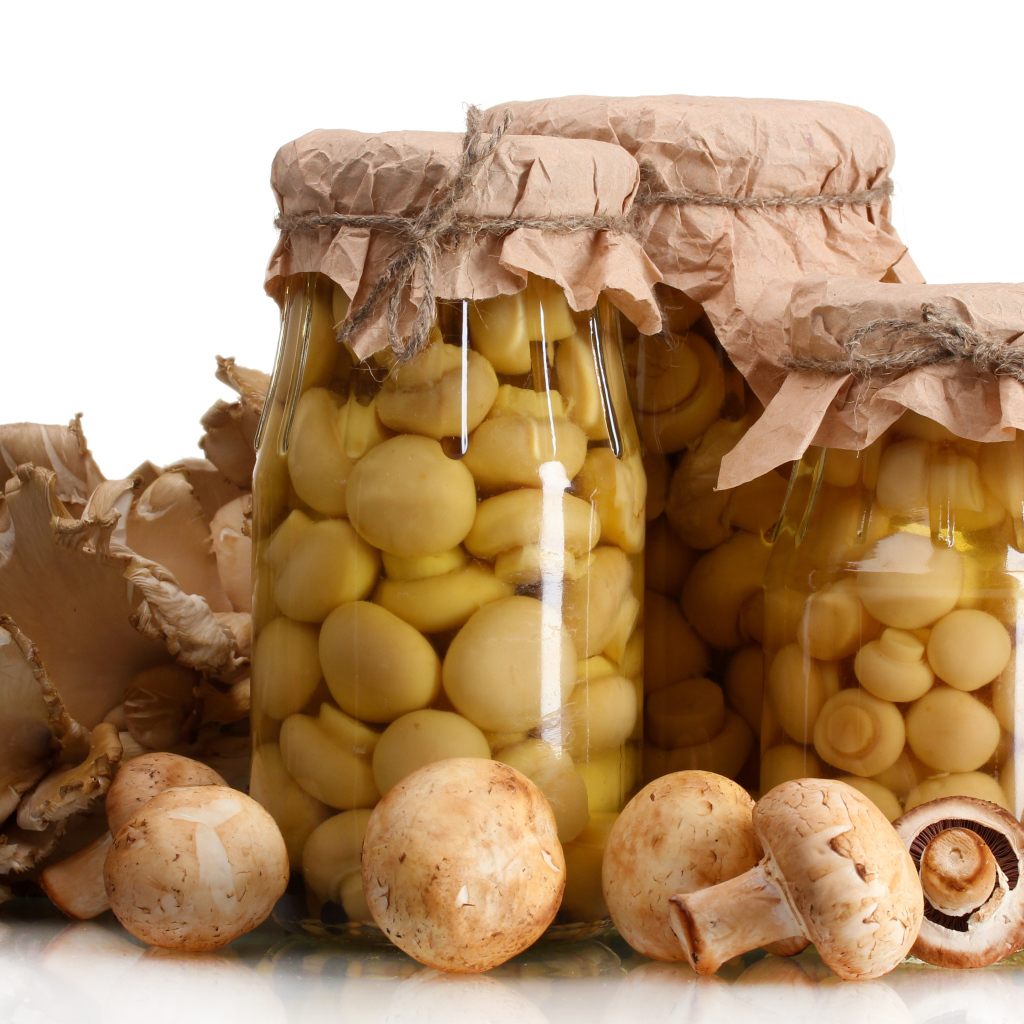 Маринованные шампиньоны в банках на белом фоне со свежими