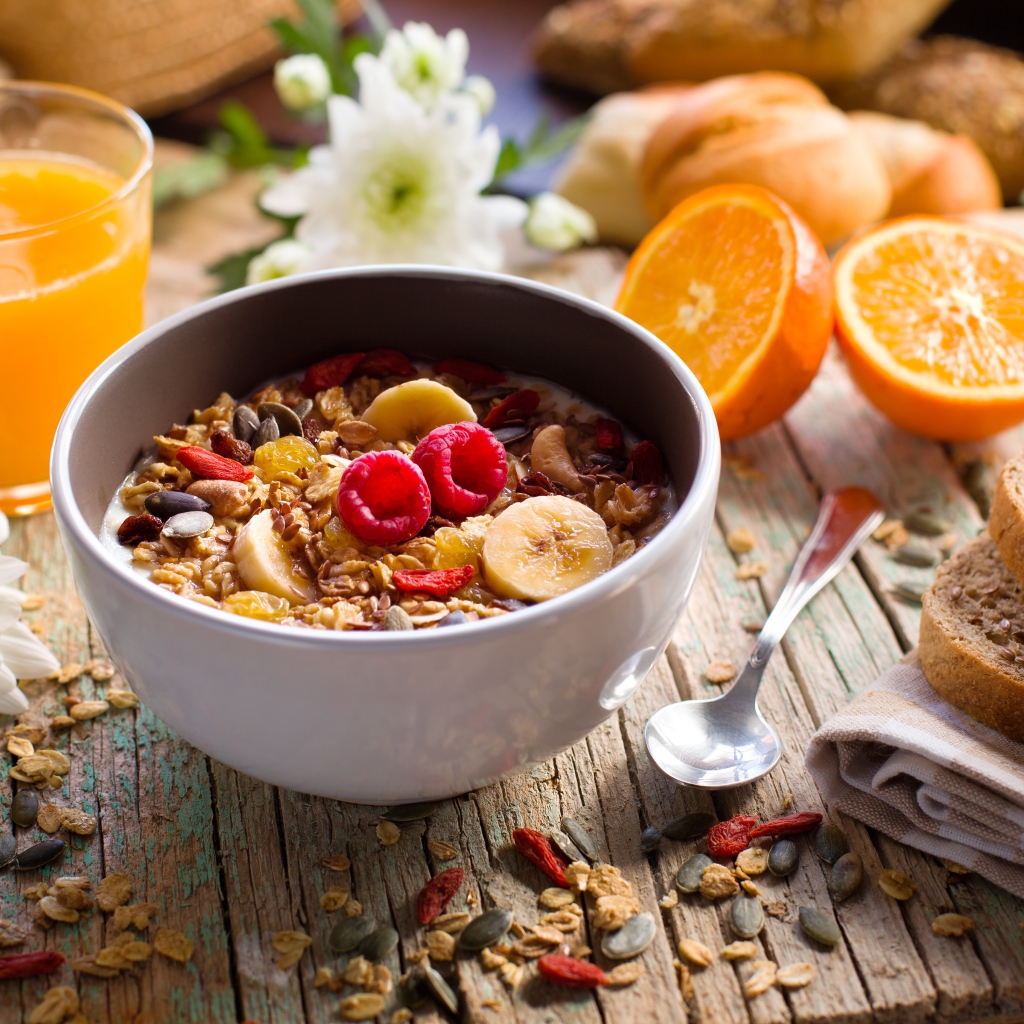Мюсли в миске с молоком на завтрак с соком и апельсинами 