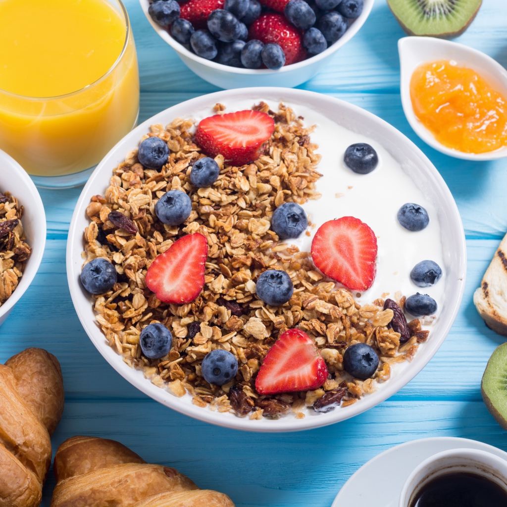 Мюсли с ягодами и молоком в тарелке на столе к завтраку