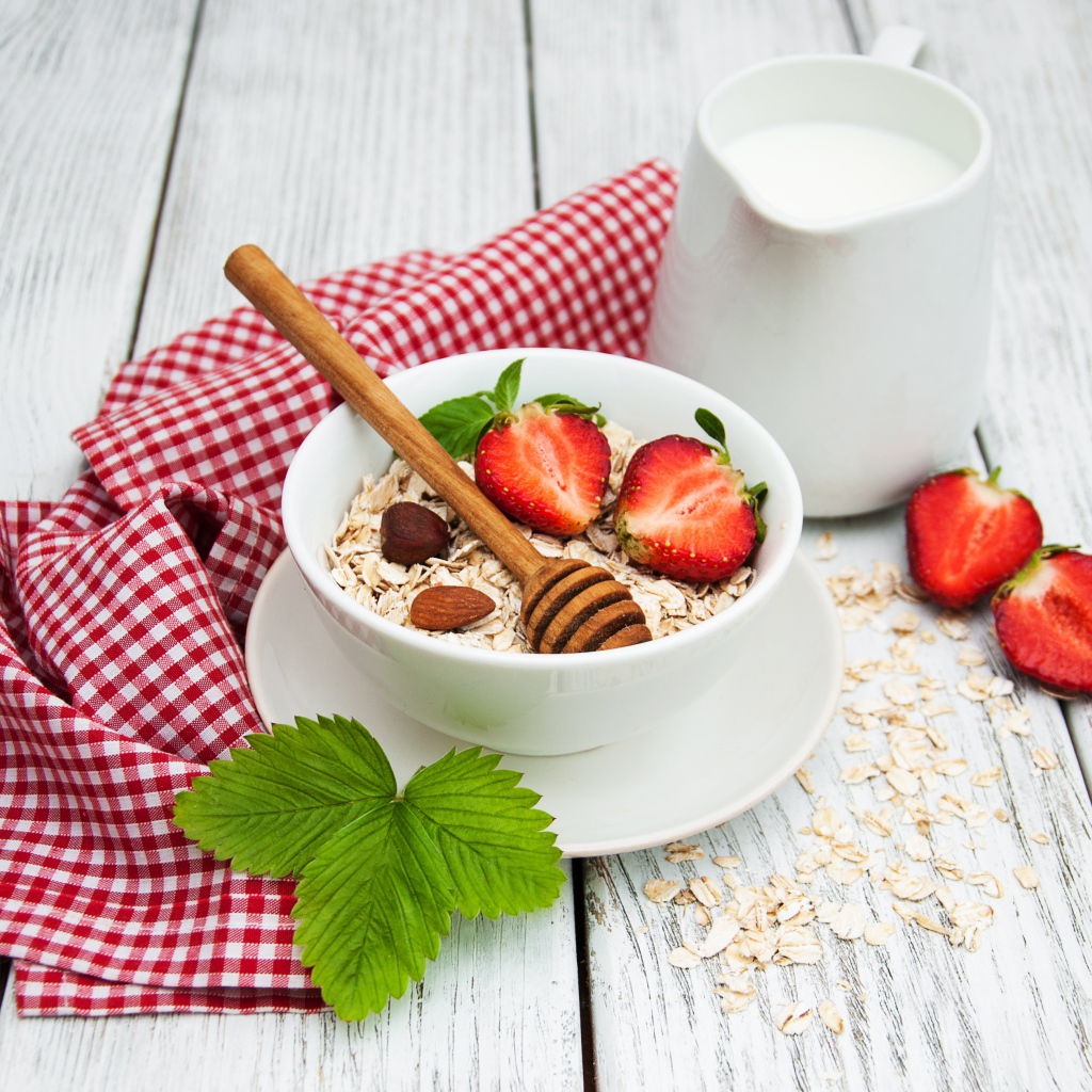 Овсяная каша на столе с молоком и клубникой