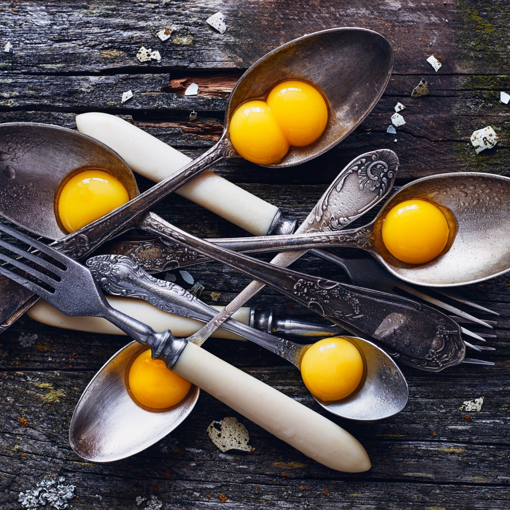 Старые ложки с желтками на деревянном столе