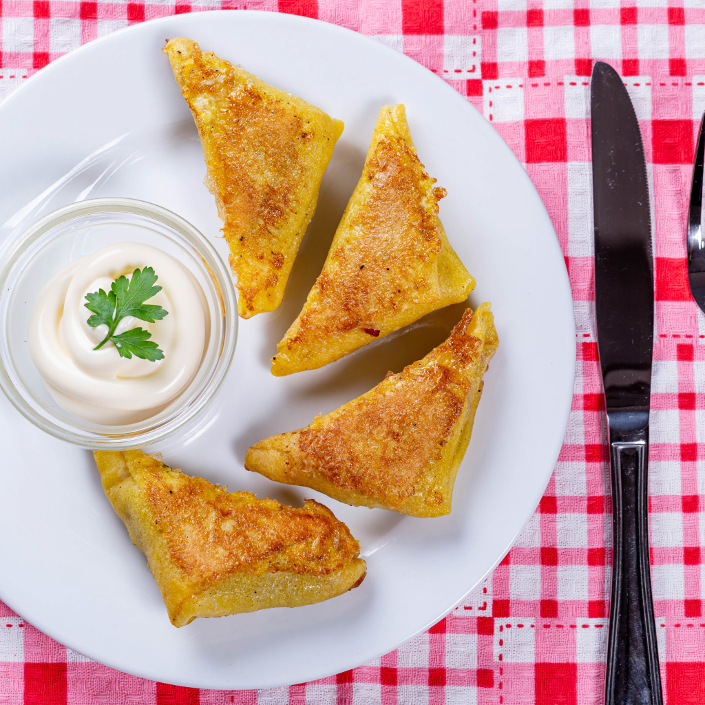 Блинчики со сметаной на столе со столовыми приборами 