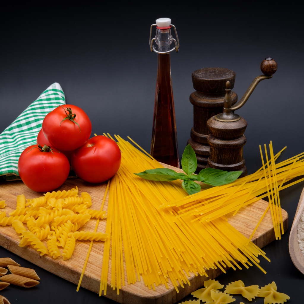 Макаронные изделия на столе с мукой, помидорами и специями