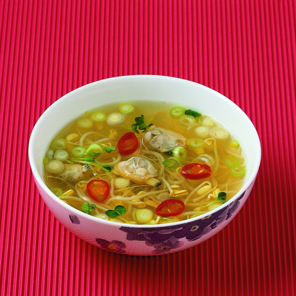 Тарелка супа с морепродуктами на красном фоне