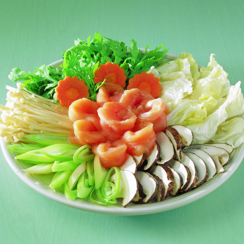 Тарелка с овощами и красной рыбой на зеленом фоне