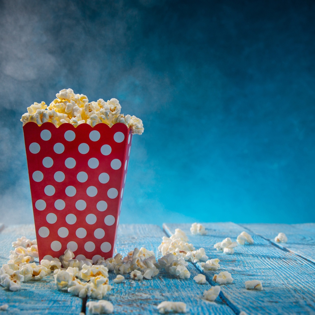Попкорн в картонном пакете на голубом столе 
