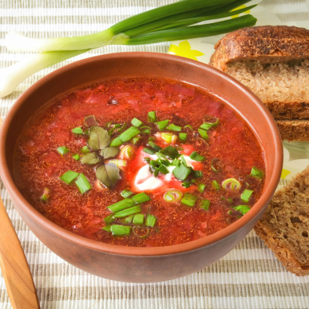 Красный борщ с луком на столе с хлебом 