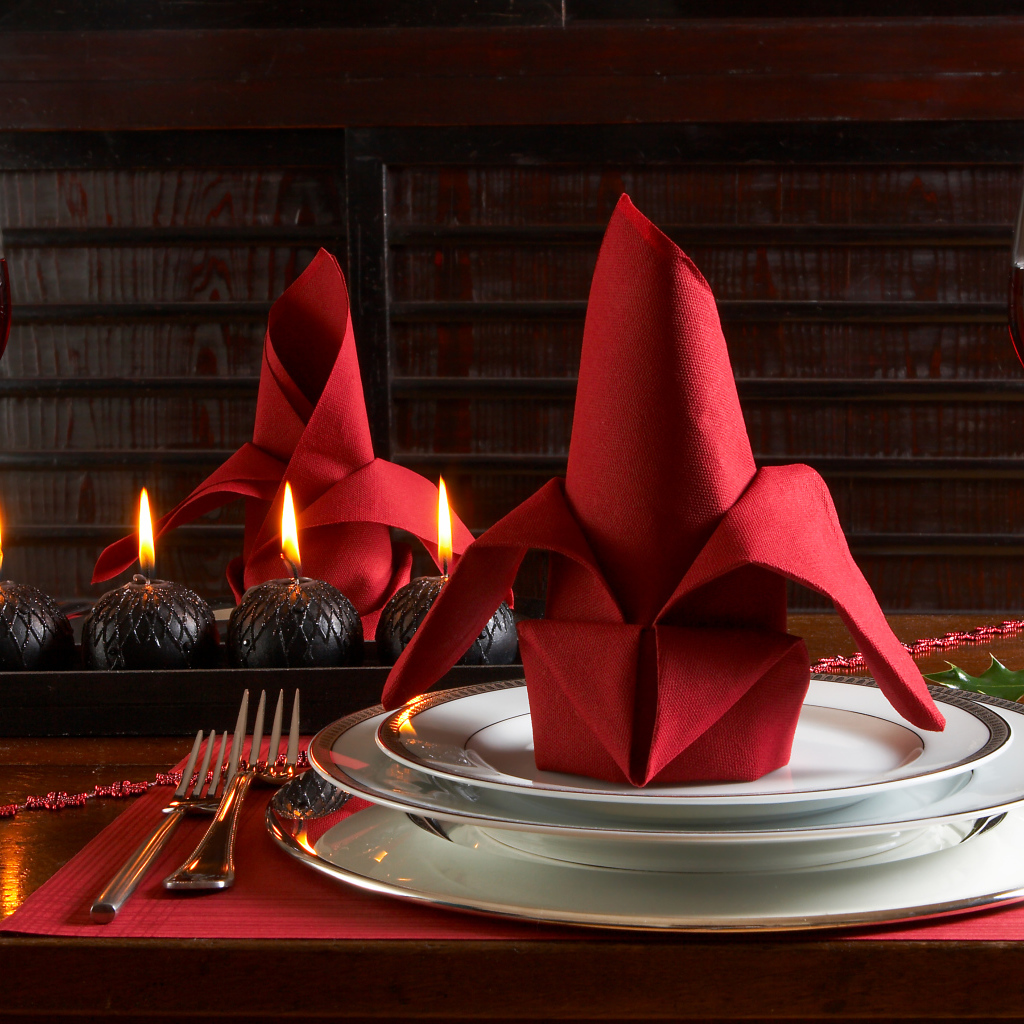 Красная салфетка на тарелке на столе с бокалами вина и свечами