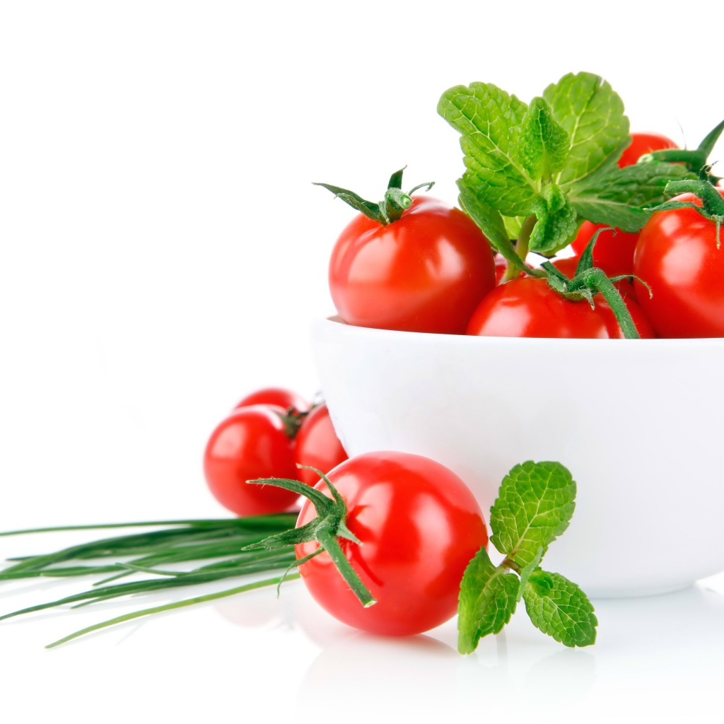 Red tomatoes with green onions on a white background