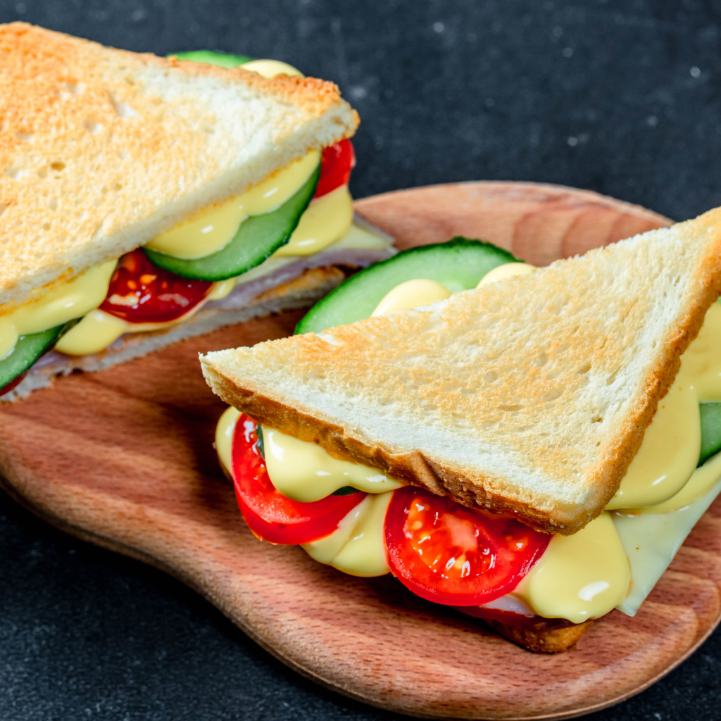 Сэндвич с сыром, помидорами и огурцами на столе