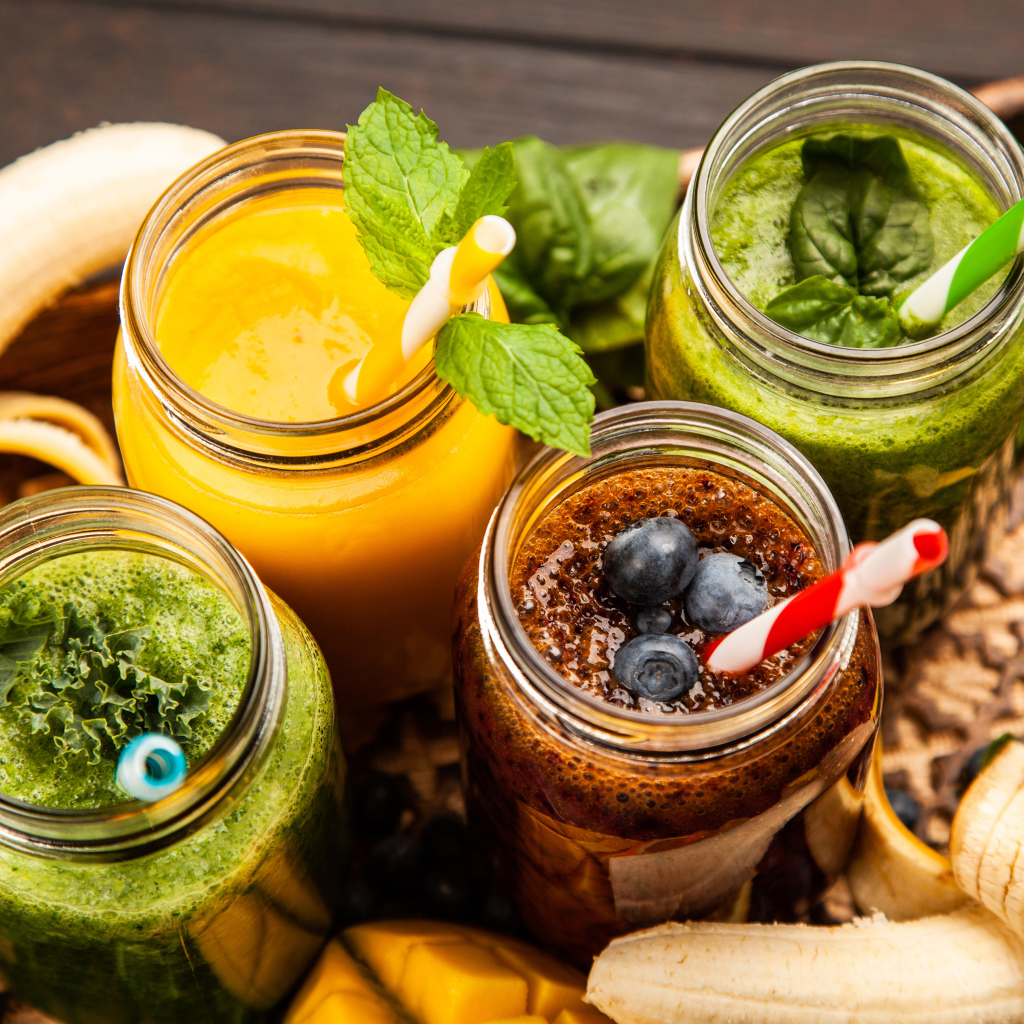 Банки со смузи на столе с бананами