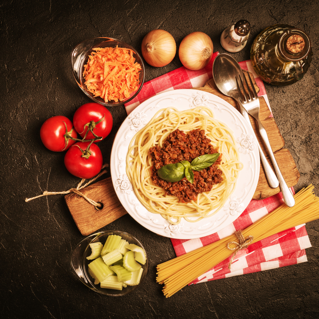 Спагетти с фаршем на столе с овощами