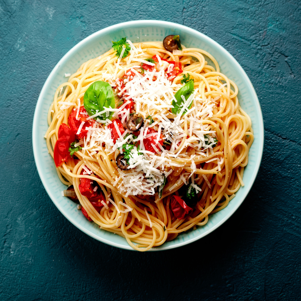 Спагетти с помидорами, сыром и базилик на столе