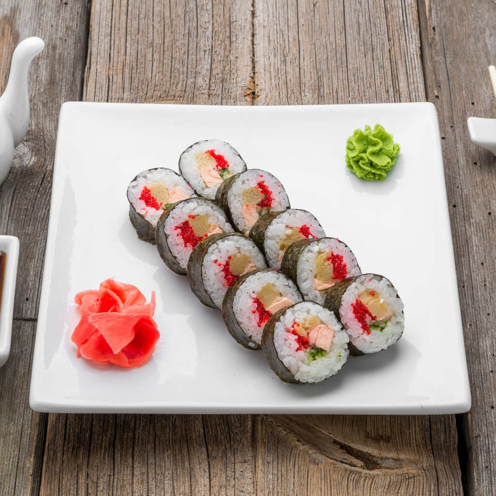 Суши на большой белой тарелке с соусом васаби и имбирем на столе соевым соусом