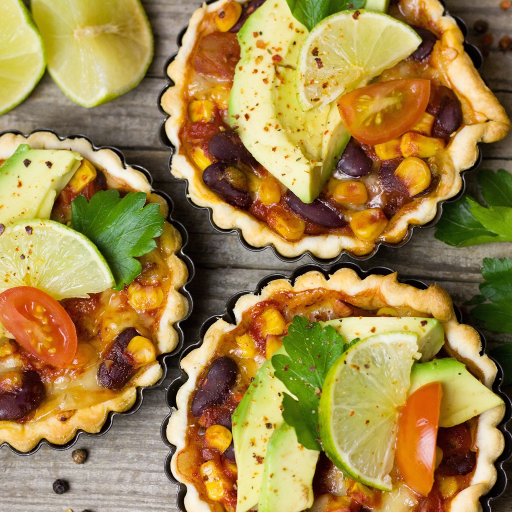 Тарталетки с блюдом, кусочками авокадо и лайма на столе