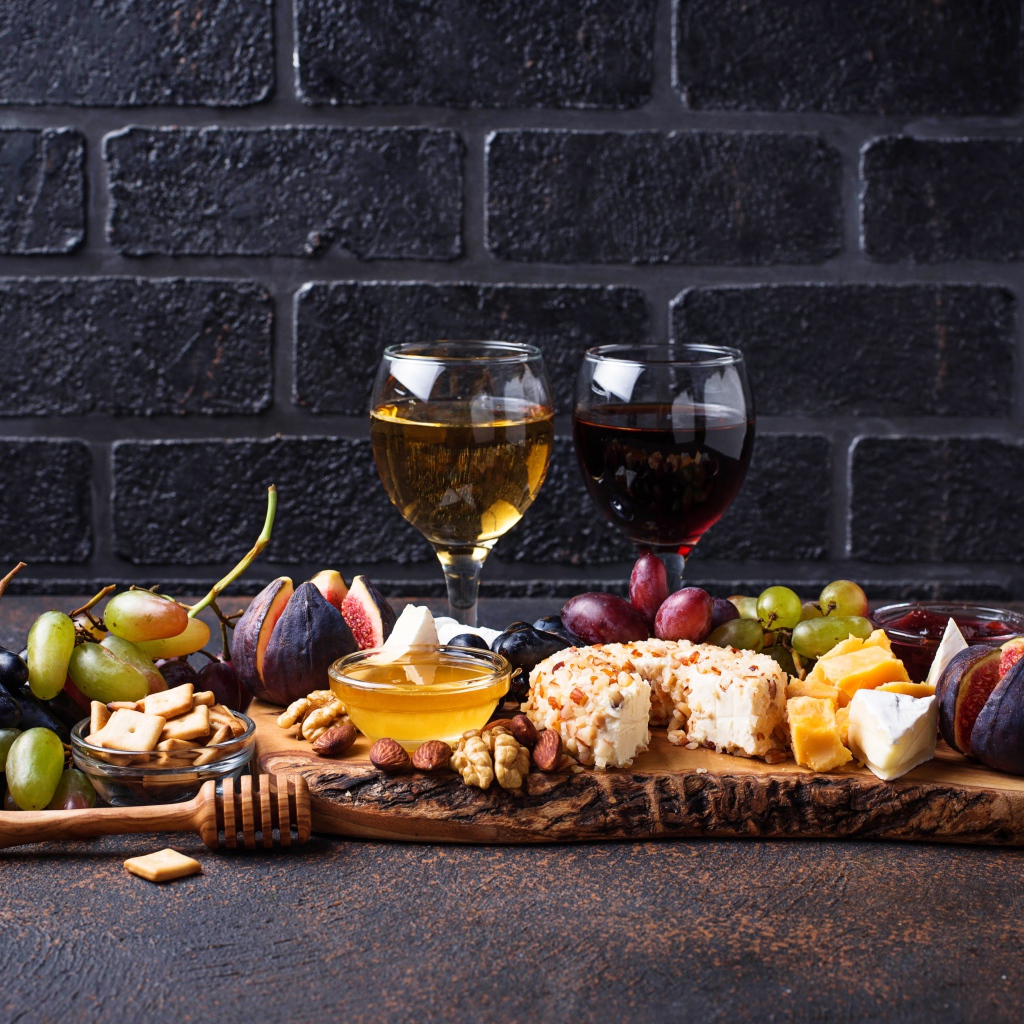 Два бокала вина на столе с сыром, инжиром и виноградом