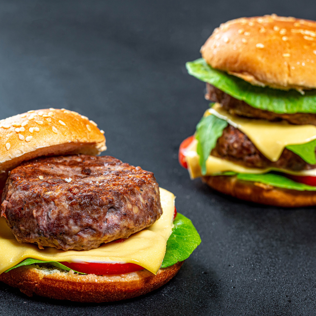 Два гамбургера с большой котлетой на столе