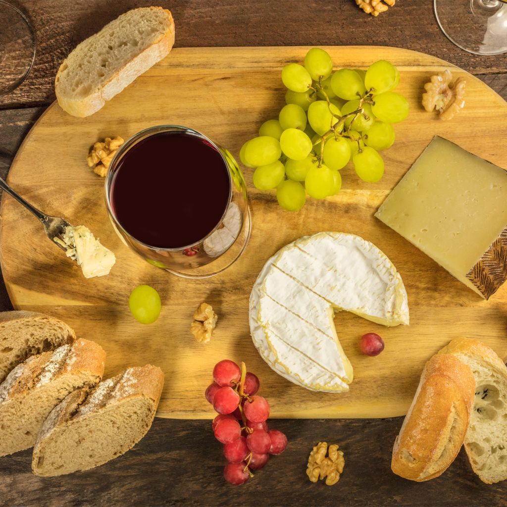 Вино, сыр, виноград и багет на столе 