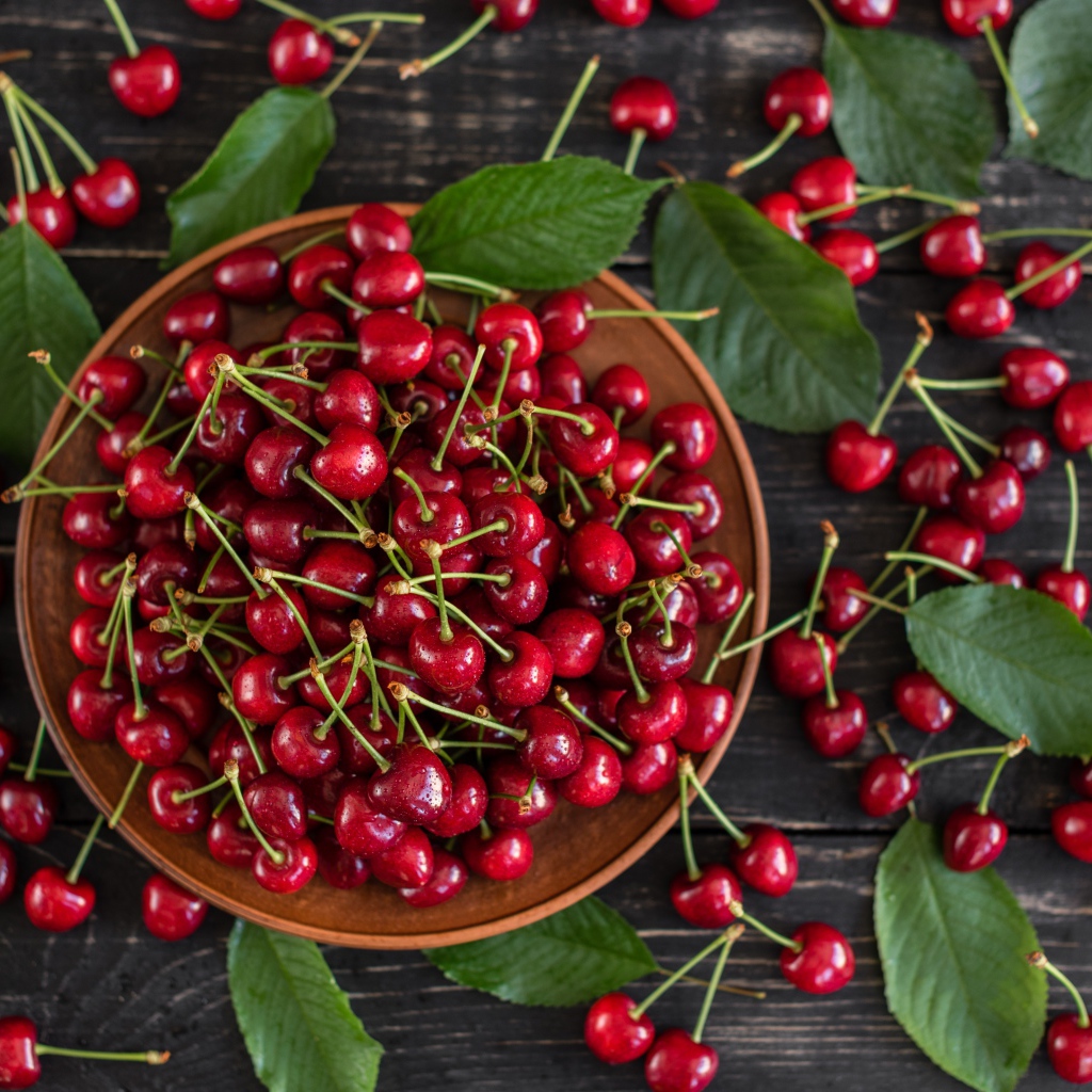 Много спелой красной черешне в миске на столе