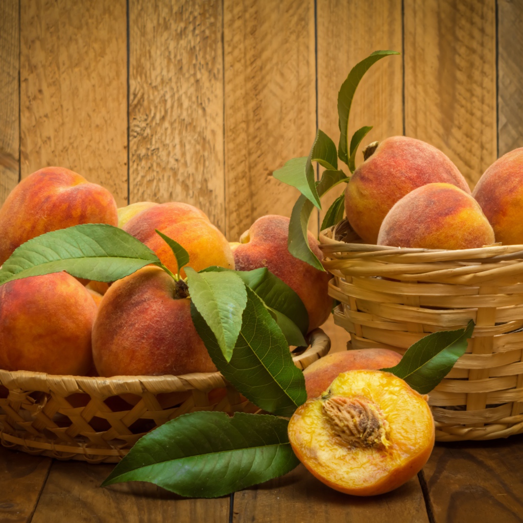 Аппетитные сочные спелые персики в корзинках на столе