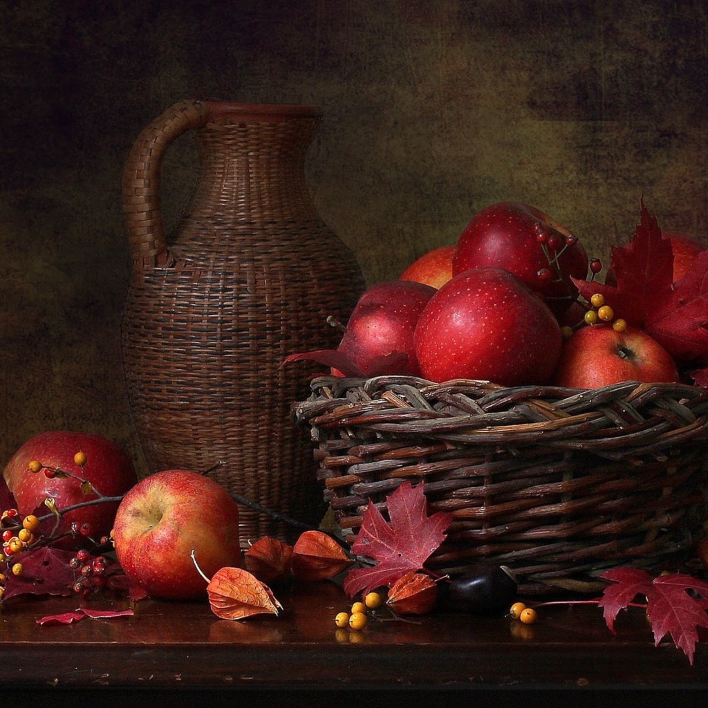 Корзина с красными яблоками на столе с кувшином 