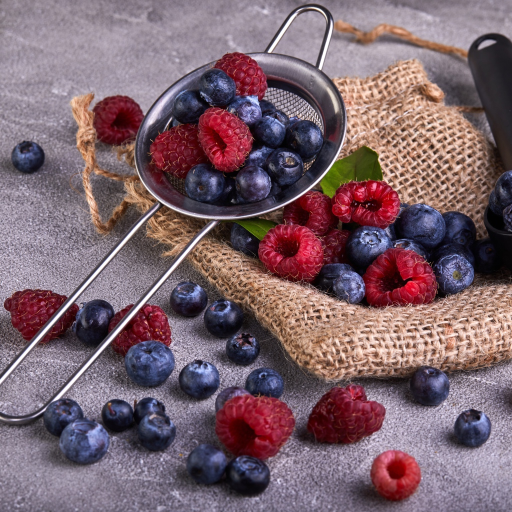 Ягоды черники и малины на столе с ситом