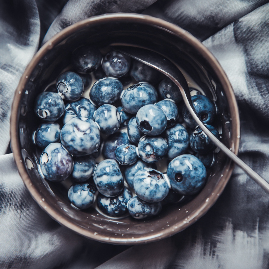 Черника в миске с йогуртом и ложкой