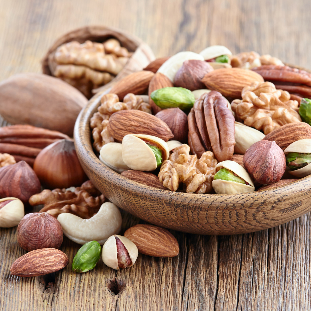 Разные орехи в деревянной тарелке на столе