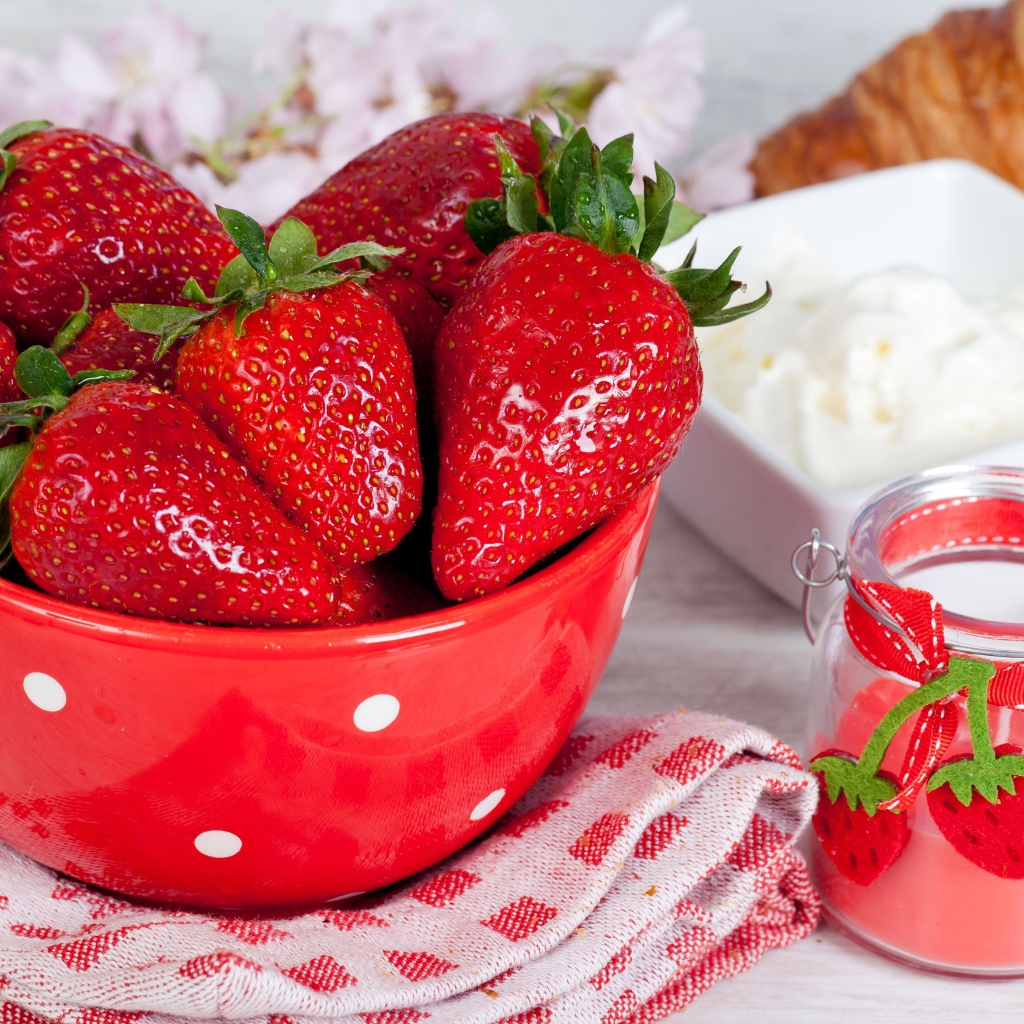 Свежие ягоды клубники в красной миске на столе