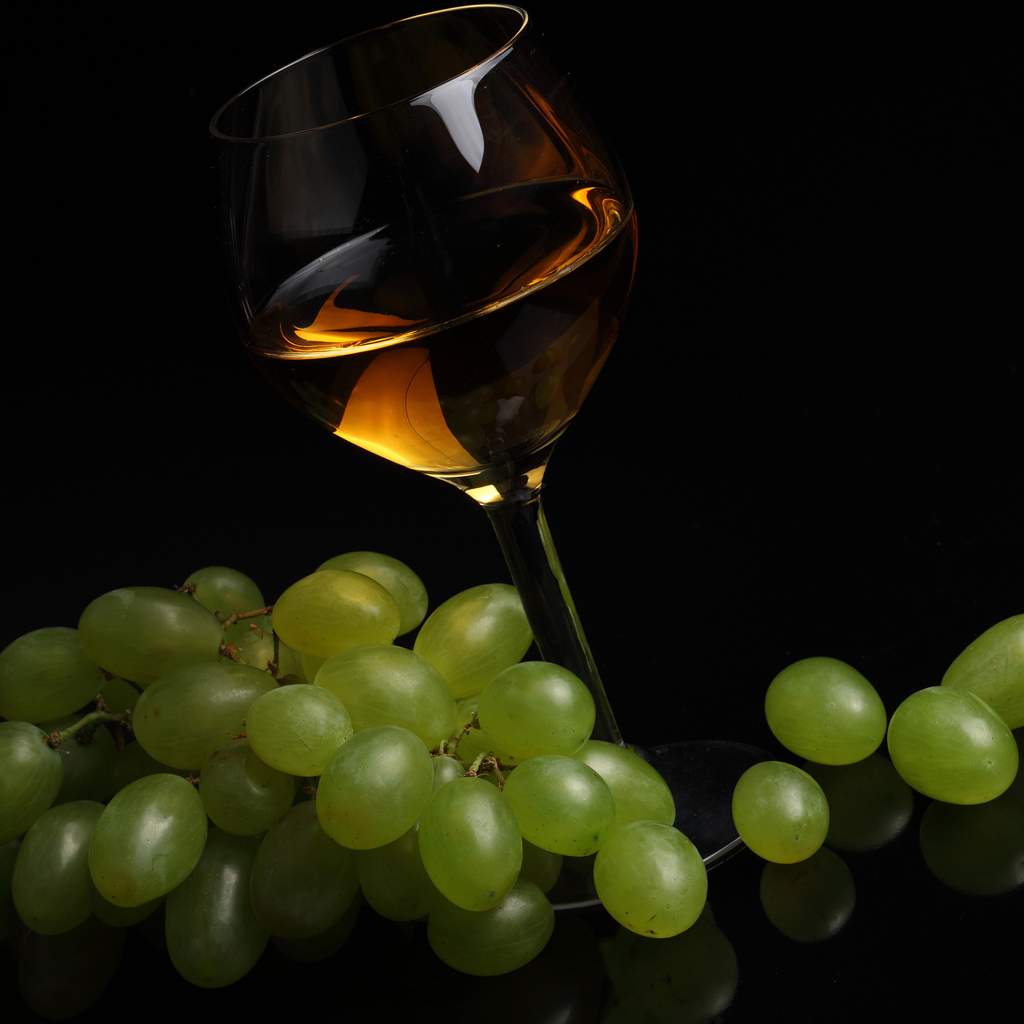 Бокал вина с белым виноградом на черном фоне
