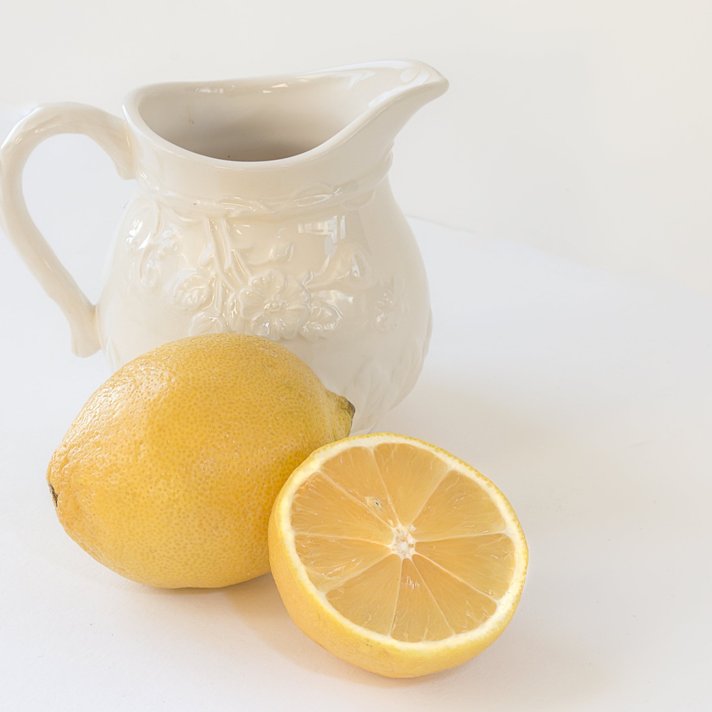 Лимон с белым кувшином на сером фоне