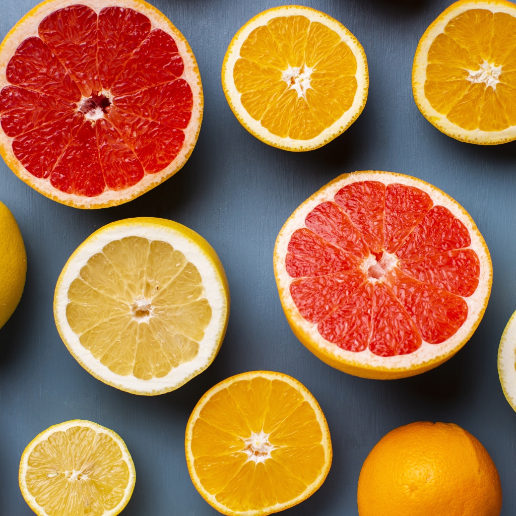 Лимоны, грепфрукты и апельсины на сером фоне