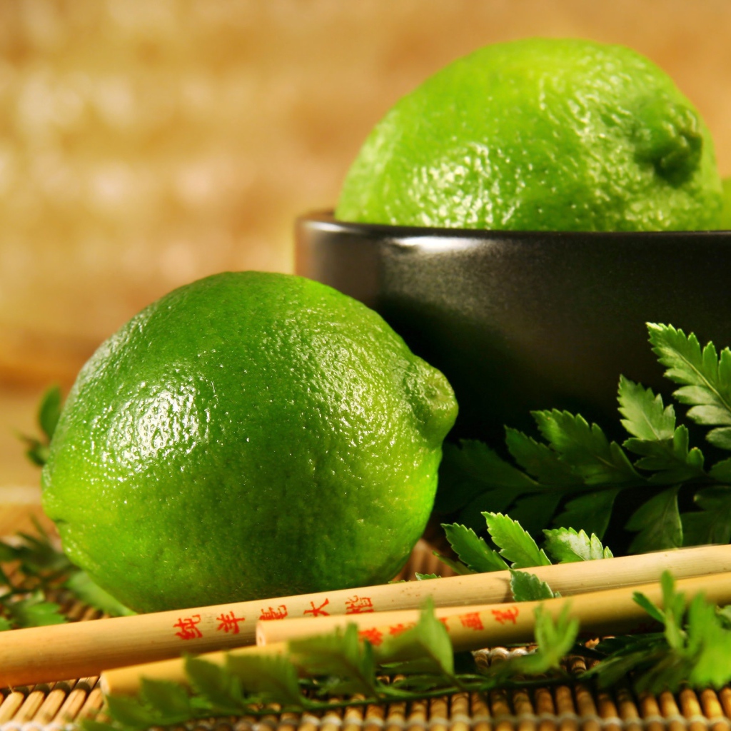 Лаймы на столе с палочками и листьями