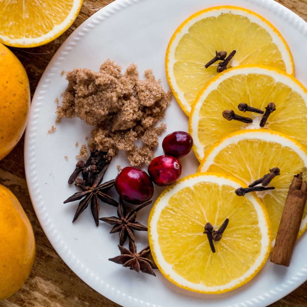 Круги апельсина на тарелке с сахаром, корицей и бадьяном