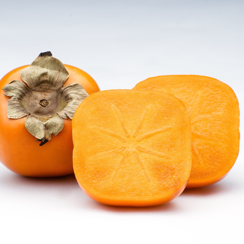 Оранжевая хурма на сером фоне крупным планом