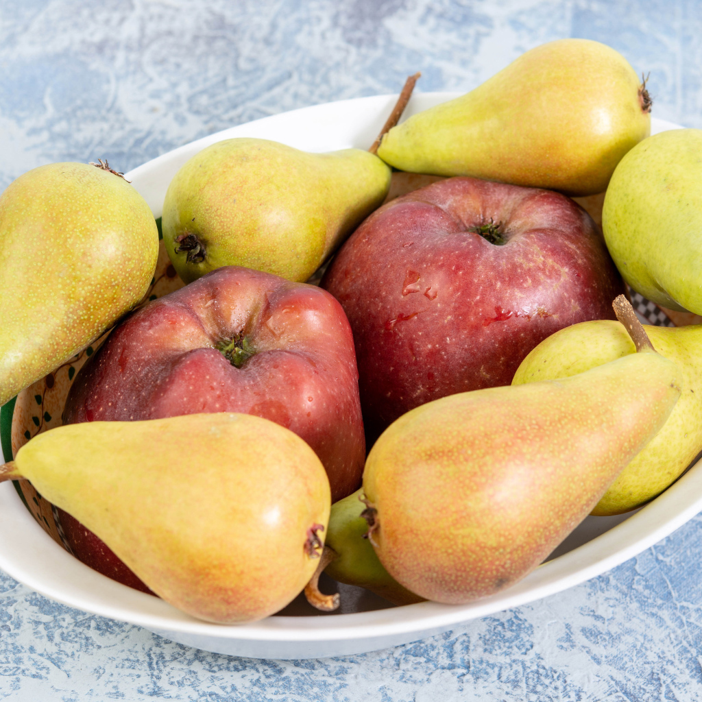 Красные яблок и груши на тарелке на столе