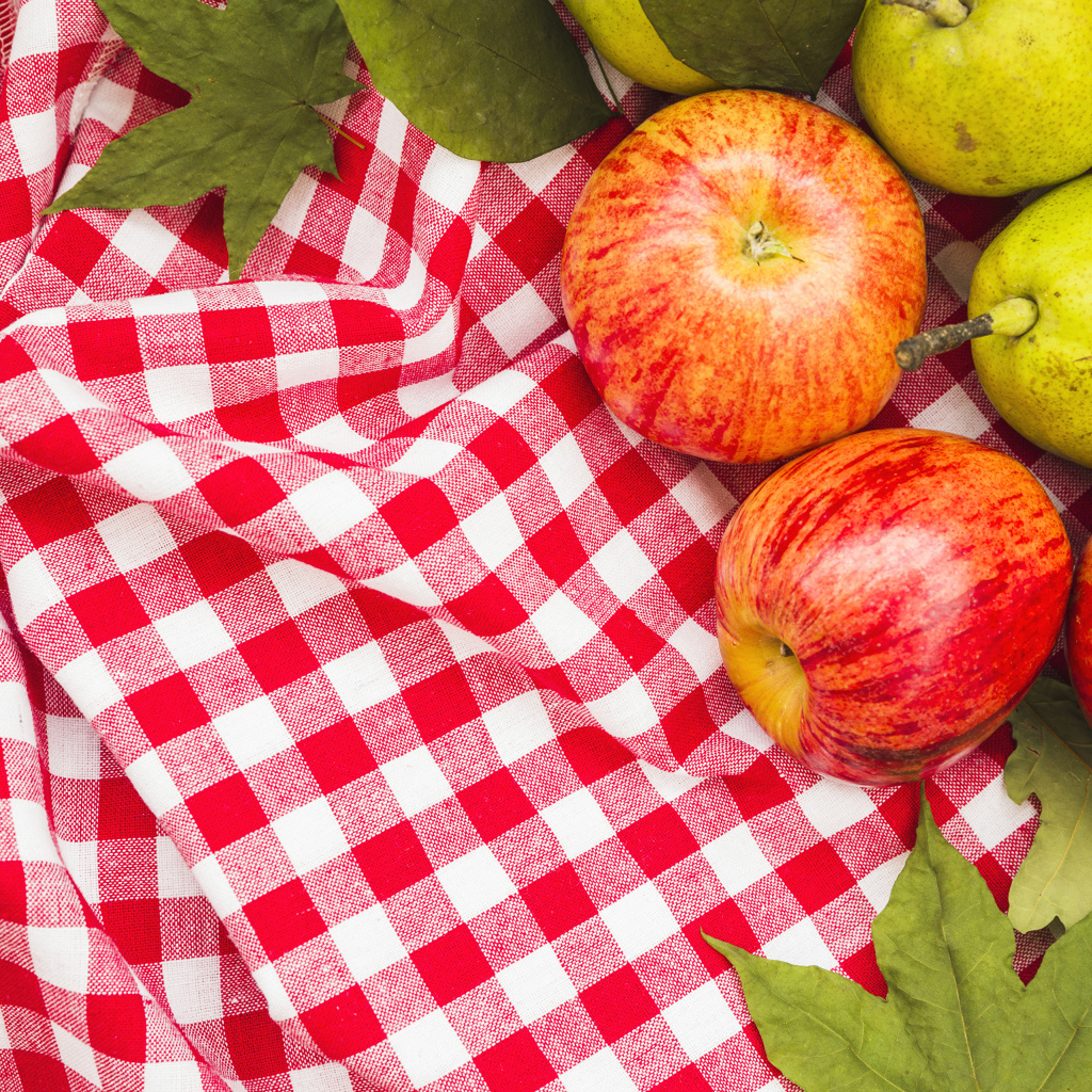 Красные яблоки с грушами на клетчатом покрывале