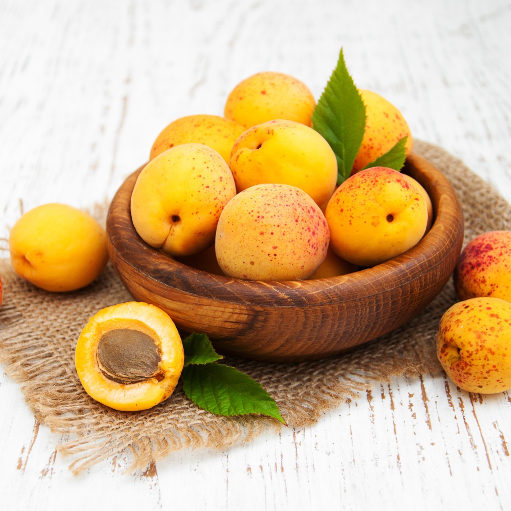 Спелые абрикосы в деревянной миске на столе