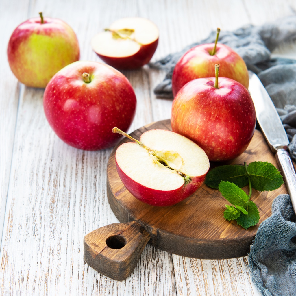 Спелые красные яблоки на разделочной доске с ножом