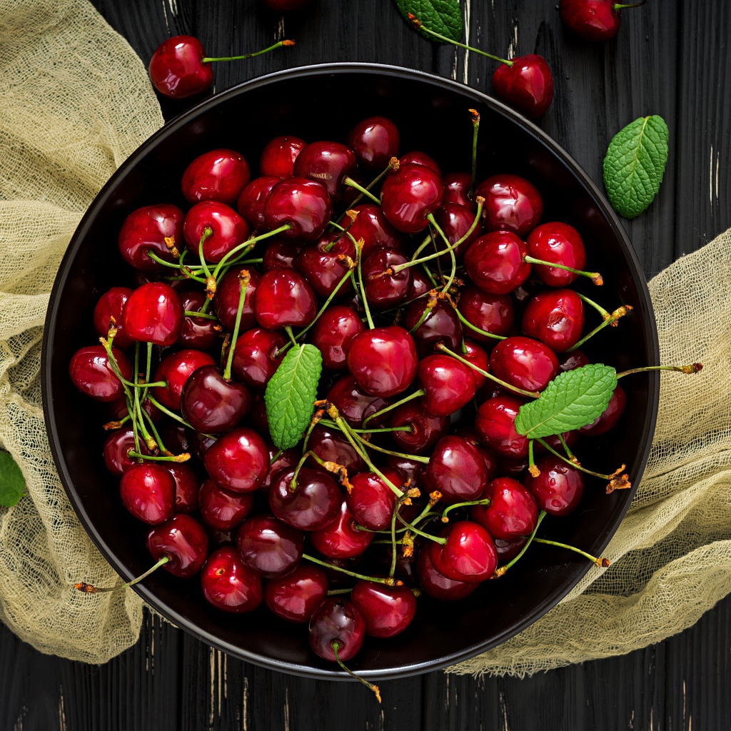 Спелые красные черешни в миске на столе