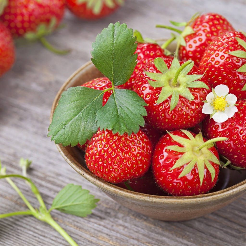 Спелая красная клубника в миске на столе 