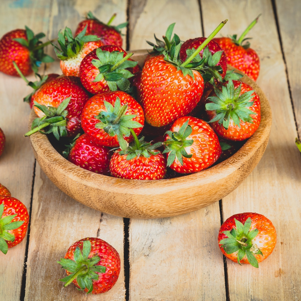 Спелая красная клубника в деревянной миске на столе